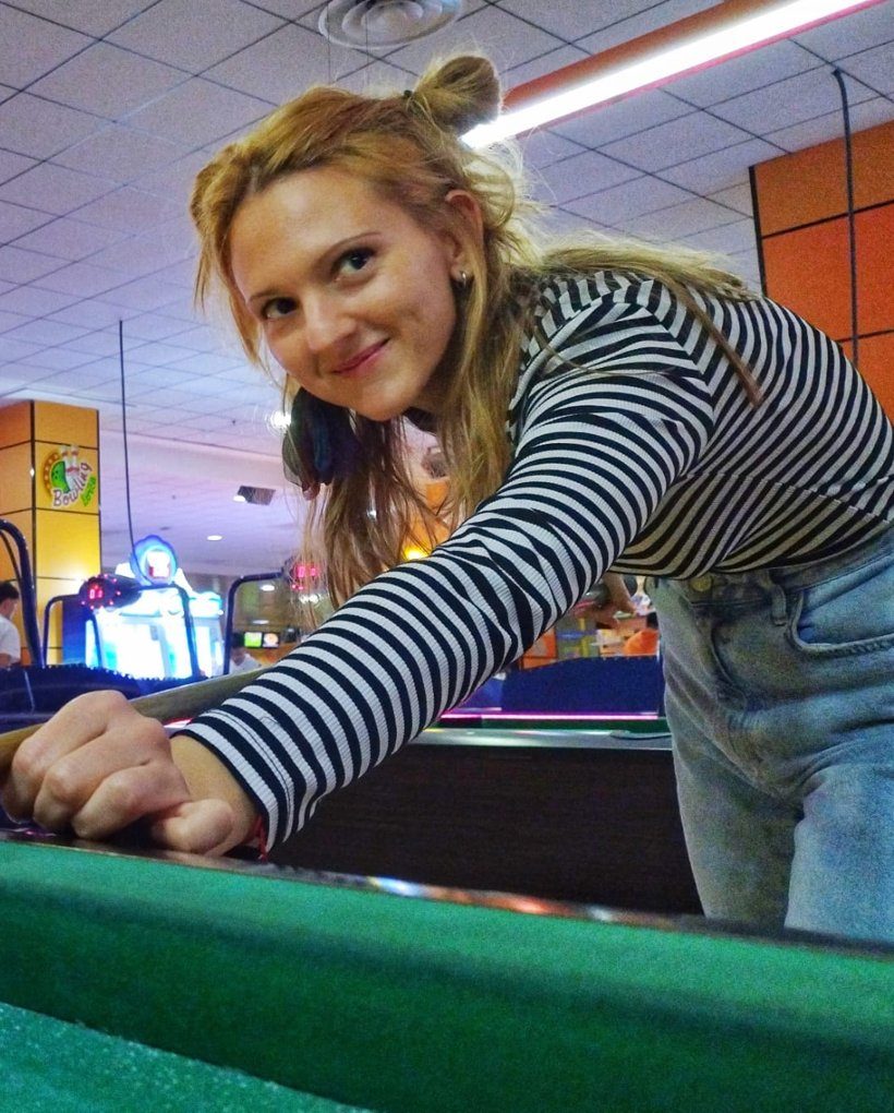 Marta, de La Marimoños, jugando al billar con sus moños y una camiseta de rayas